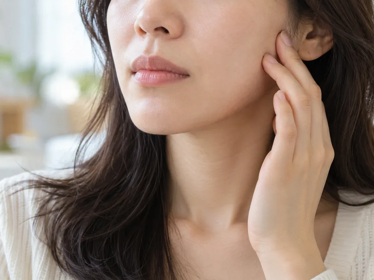 입을 다물고 위아래 치아를 가볍게 맞물어 보며 턱 옆에 손끝을 대고 있는 모습 — 리셋치과의원